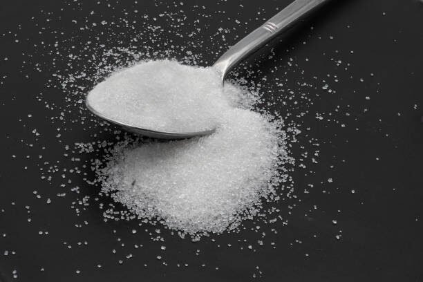 Spoon of sugar on a black background.